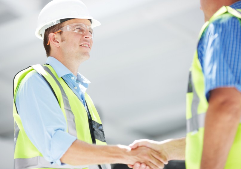 Two engineers shaking hands on a construction site